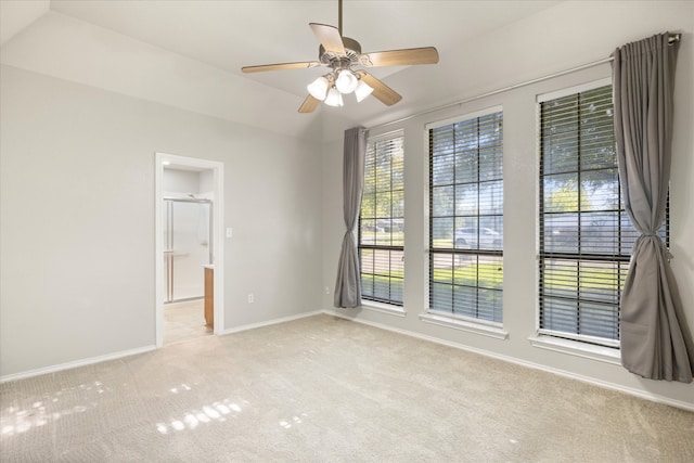 spare room featuring vaulted ceiling, ceiling fan, and light colored carpet