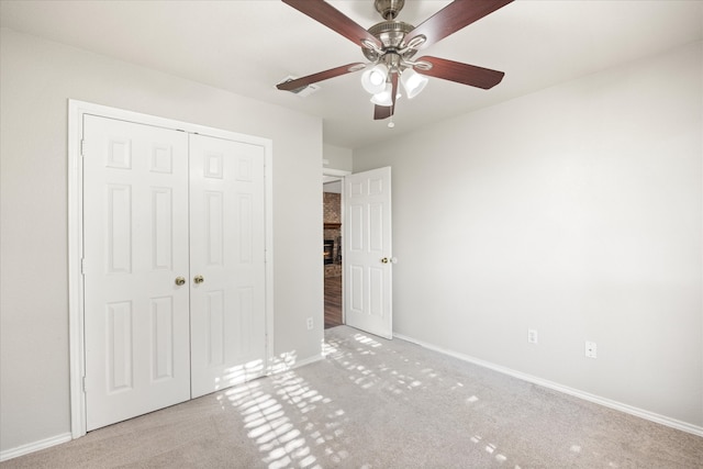 unfurnished bedroom with ceiling fan, a closet, and light carpet