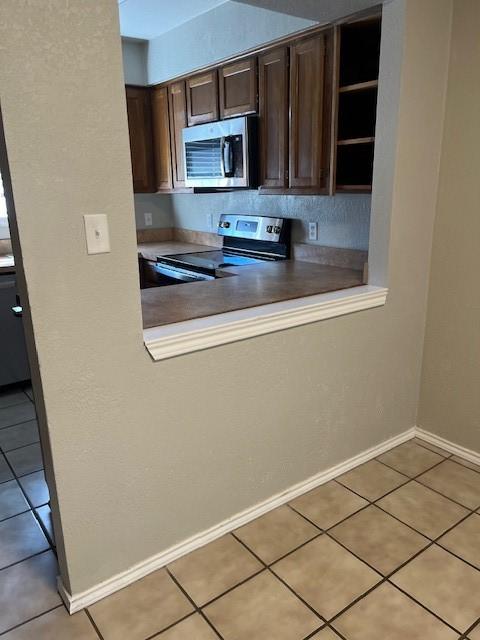 kitchen with light tile patterned flooring, appliances with stainless steel finishes, and dark brown cabinetry