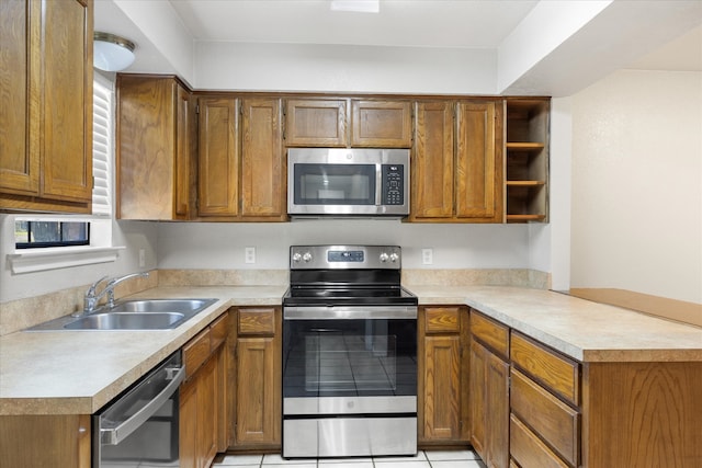 kitchen featuring light tile patterned floors, kitchen peninsula, sink, and stainless steel appliances