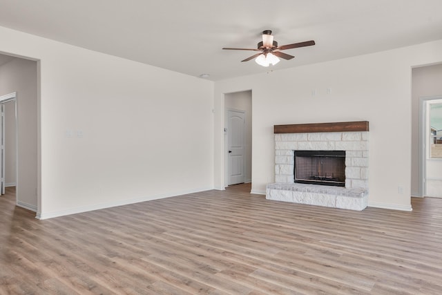 10 Louis Rd, Sherman, TX 75090 - unfurnished living room featuring a stone fireplace, wood finished floors, a ceiling fan, and baseboards