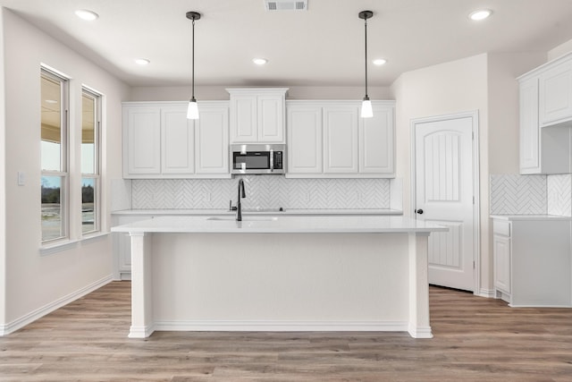 10 Louis Rd, Sherman, TX 75090 - kitchen with a sink, light wood-style floors, light countertops, stainless steel microwave, and an island with sink