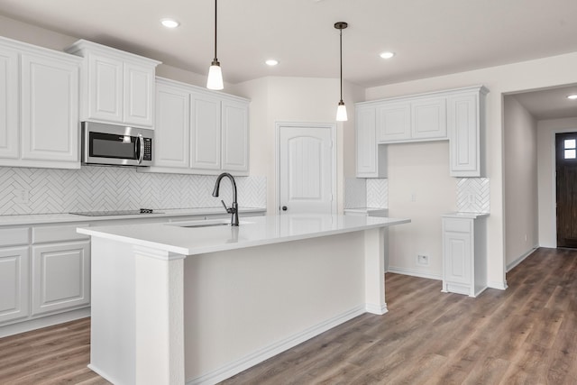 10 Louis Rd, Sherman, TX 75090 - kitchen featuring a kitchen island with sink, wood finished floors, a sink, light countertops, and stainless steel microwave
