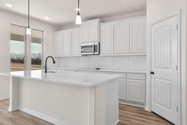 10 Louis Rd, Sherman, TX 75090 - kitchen with wood finished floors, a sink, tasteful backsplash, stainless steel microwave, and a center island with sink