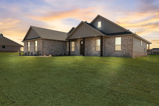 view of front of house featuring a front lawn, board and batten siding, and brick siding