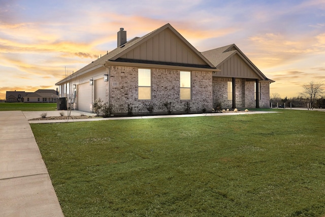 view of front facade featuring brick siding, a yard, an attached garage, board and batten siding, and driveway