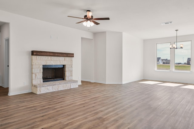 10 Louis Rd, Sherman, TX 75090 - unfurnished living room featuring a stone fireplace, ceiling fan with notable chandelier, wood finished floors, visible vents, and baseboards
