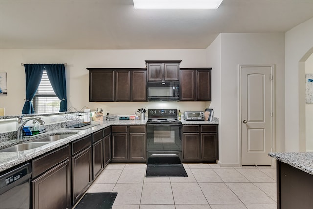 kitchen with light stone countertops, light tile patterned floors, black appliances, dark brown cabinetry, and sink