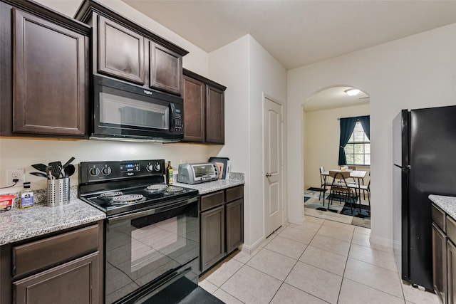 kitchen with black appliances, light tile patterned flooring, dark brown cabinetry, and light stone counters