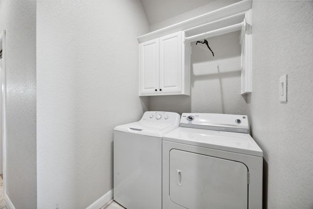 clothes washing area featuring washer and clothes dryer and cabinets