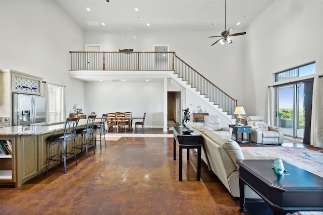 living room with a towering ceiling and ceiling fan