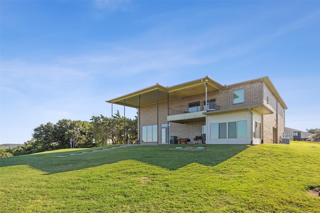 rear view of house with a balcony and a yard