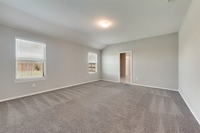 unfurnished room featuring lofted ceiling, plenty of natural light, and carpet flooring