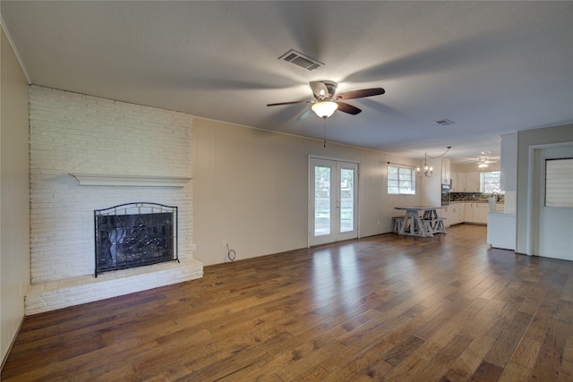 unfurnished living room with ceiling fan, french doors, a textured ceiling, a fireplace, and dark hardwood / wood-style flooring