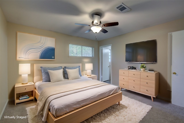 bedroom featuring dark colored carpet, ceiling fan, and ensuite bath