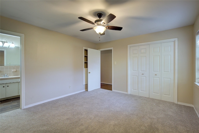 unfurnished bedroom with ceiling fan, ensuite bathroom, sink, and carpet flooring