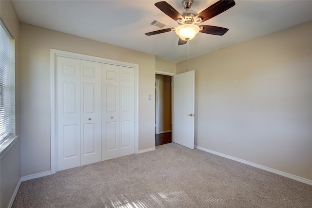 unfurnished bedroom featuring ceiling fan, light colored carpet, and a closet