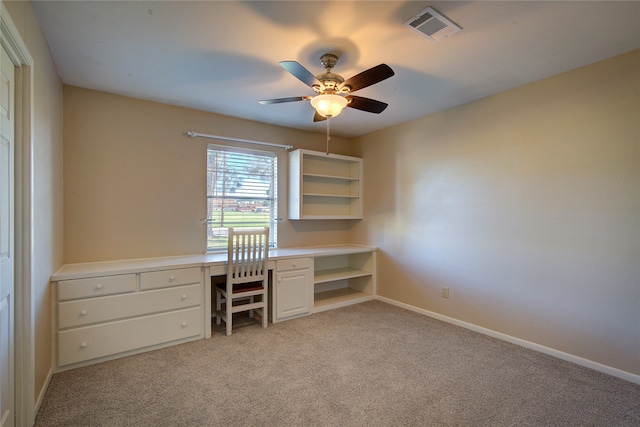 unfurnished office featuring light carpet, built in desk, and ceiling fan