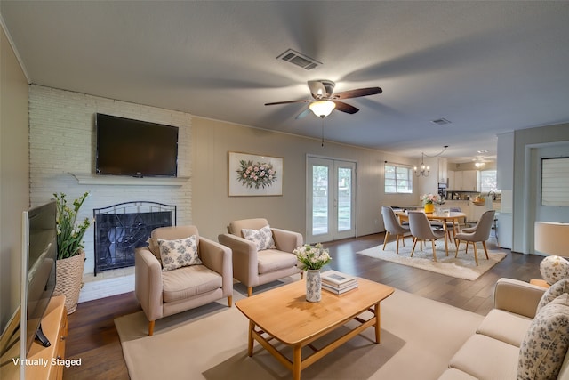 living room with a brick fireplace, french doors, dark wood-type flooring, and ceiling fan