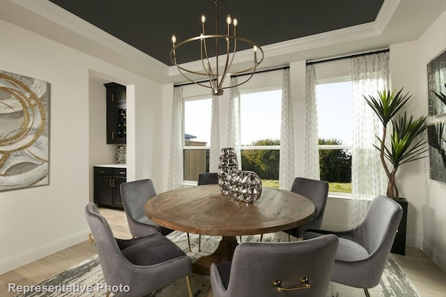 dining area featuring a notable chandelier, light wood-type flooring, a tray ceiling, and ornamental molding