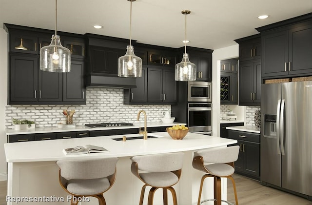 kitchen with an island with sink, stainless steel appliances, sink, and tasteful backsplash