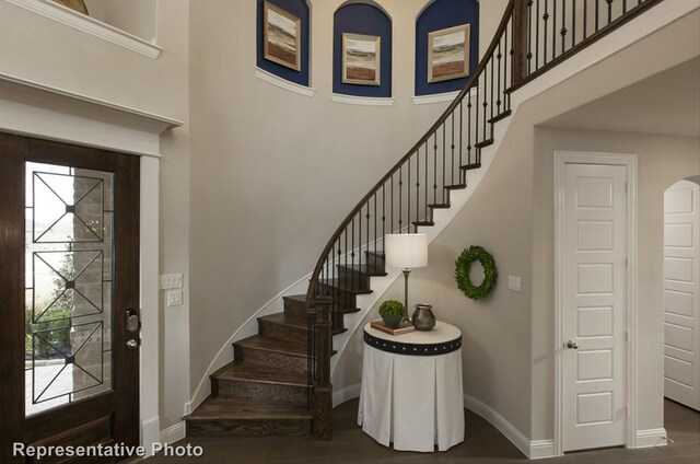 stairs featuring hardwood / wood-style flooring, a towering ceiling, and a wealth of natural light