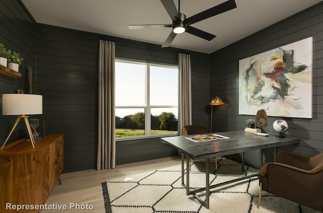 office with light wood-type flooring, wood walls, and ceiling fan