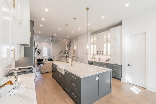 kitchen featuring gray cabinetry, light wood-style floors, open floor plan, white cabinetry, and light stone countertops