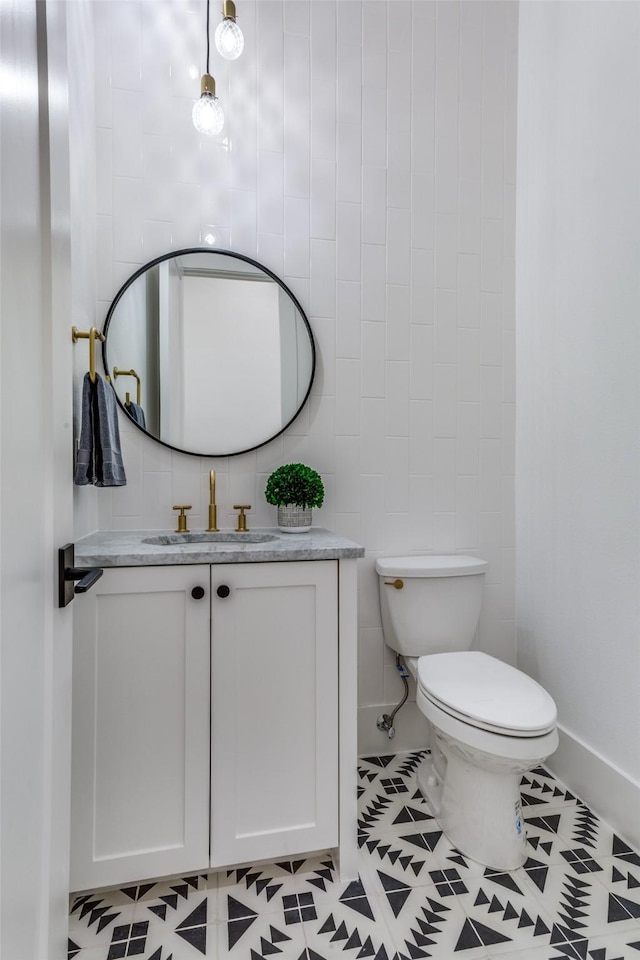 half bathroom featuring toilet, tile patterned flooring, vanity, and baseboards