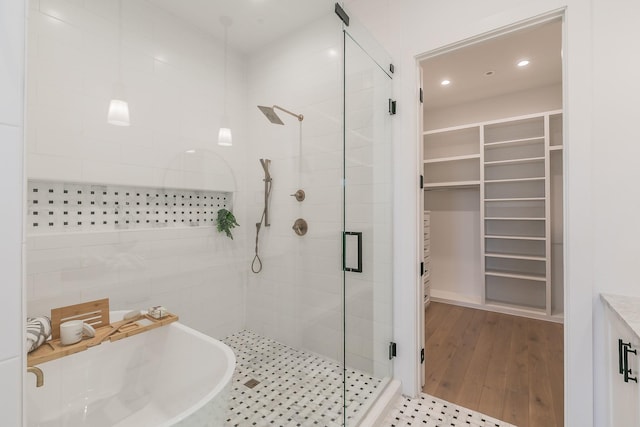 bathroom featuring a stall shower, a walk in closet, a sink, and recessed lighting