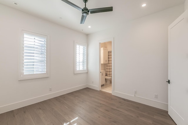 unfurnished bedroom featuring recessed lighting, connected bathroom, baseboards, and wood finished floors