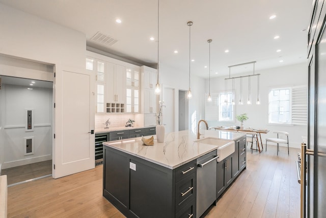 kitchen featuring light wood finished floors, visible vents, white cabinetry, a sink, and dark cabinets