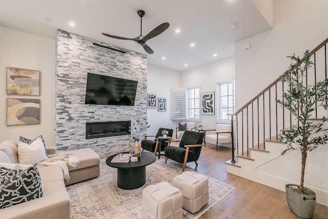 living room featuring a ceiling fan, hardwood / wood-style floors, stairs, a fireplace, and recessed lighting