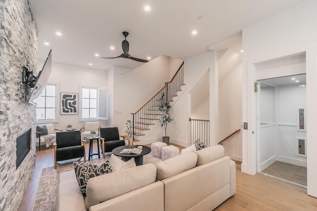 living area with stairs, recessed lighting, a fireplace, and wood finished floors