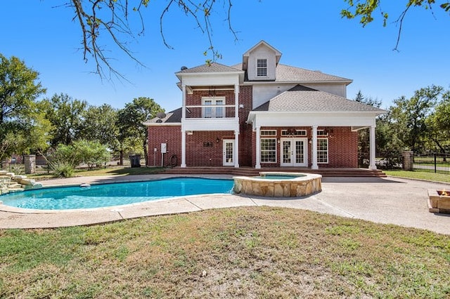 back of property with a patio, a yard, a balcony, a pool with hot tub, and french doors