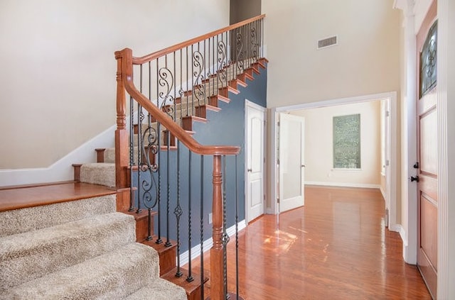 stairs with hardwood / wood-style floors and a high ceiling