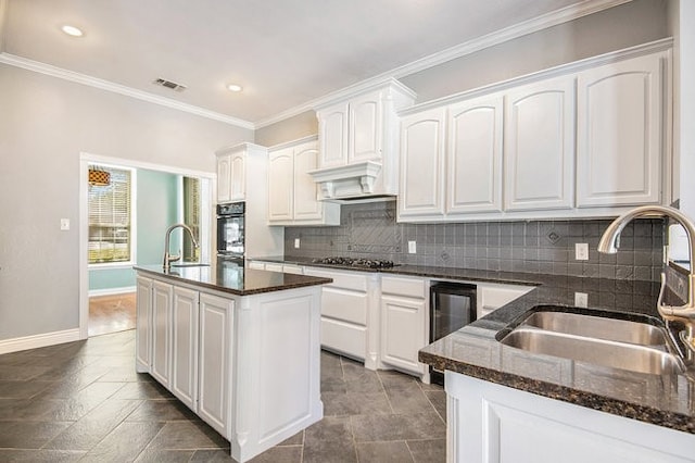 kitchen featuring white cabinets, wine cooler, a center island, and sink