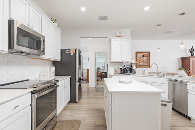 kitchen featuring light hardwood / wood-style flooring, appliances with stainless steel finishes, a center island, and white cabinetry