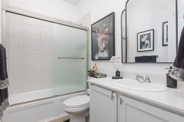 full bathroom with enclosed tub / shower combo, vanity, and toilet