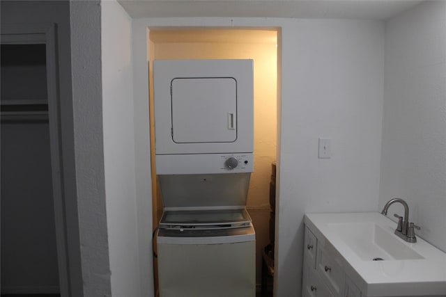 clothes washing area with stacked washer / drying machine and sink