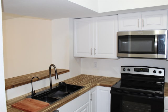 kitchen with butcher block countertops, white cabinetry, sink, and black / electric stove