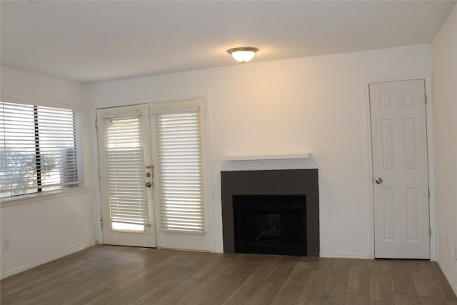 unfurnished living room featuring wood-type flooring and a brick fireplace