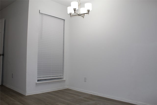 empty room with dark hardwood / wood-style floors and an inviting chandelier