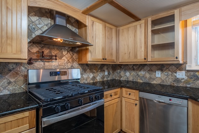 kitchen with appliances with stainless steel finishes, dark stone counters, wall chimney range hood, and tasteful backsplash