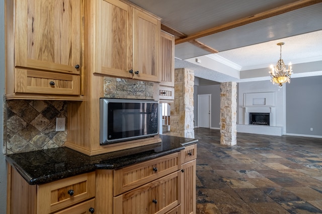 kitchen with pendant lighting, backsplash, light brown cabinets, and an inviting chandelier