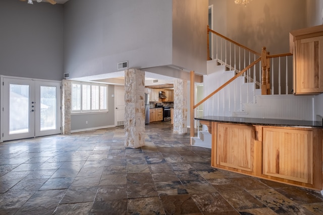 kitchen featuring light brown cabinets, stainless steel appliances, ornate columns, a high ceiling, and french doors