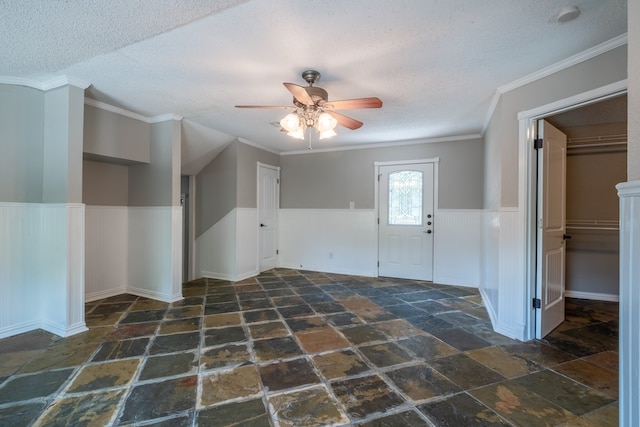 entryway with ceiling fan, a textured ceiling, and ornamental molding