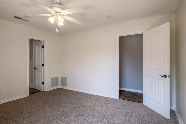 interior space with a textured ceiling, dark carpet, and ceiling fan