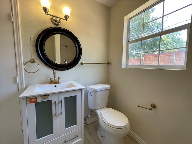 bathroom with toilet, hardwood / wood-style floors, and vanity