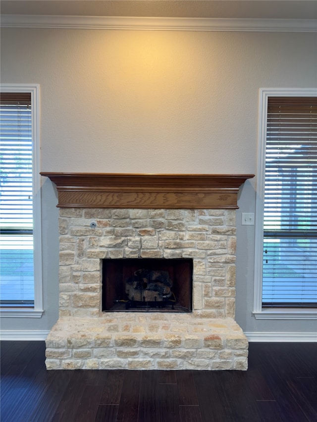 room details featuring a stone fireplace, hardwood / wood-style flooring, and crown molding